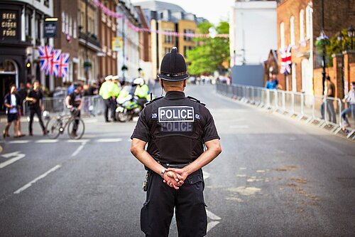 A Police Officer stood in the middle of a close road.