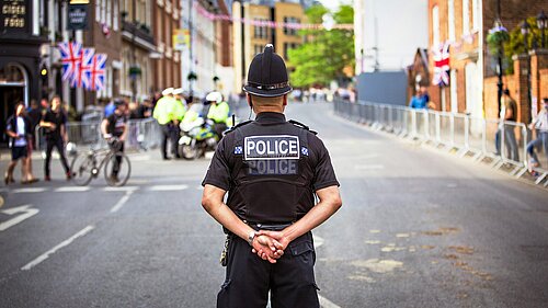 A Police Officer stood in the middle of a close road.