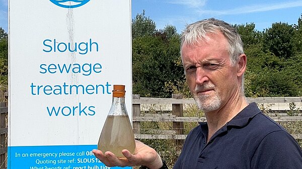 Mark Wilson holding a container of river water 