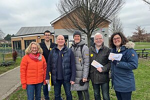 a group of men and women in warm coats stand outside holiding Lib Dem Leaflets